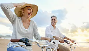 senior couple biking at beach