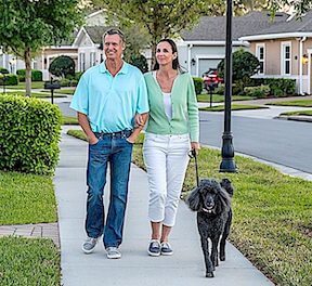 senior couple out walking dog in retirement community by Kolter Homes